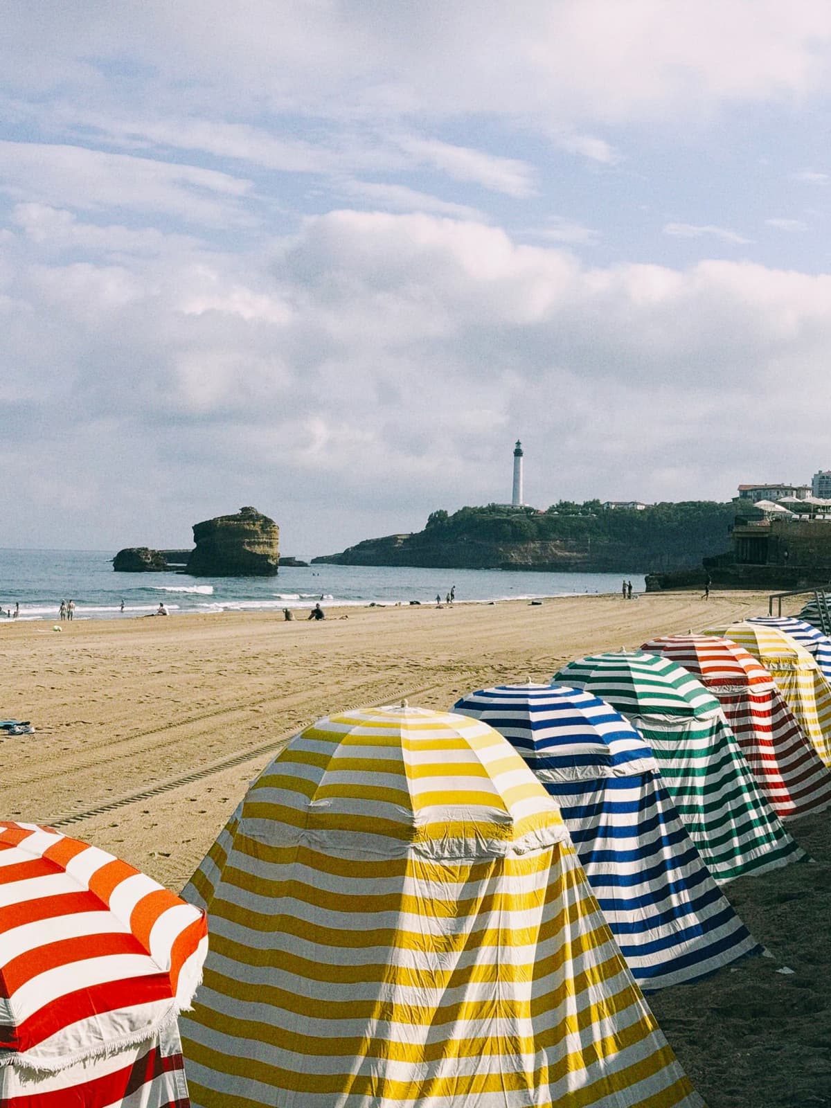 Striped tents down the Grande Plage, the lighthouse keeping watch from its headland