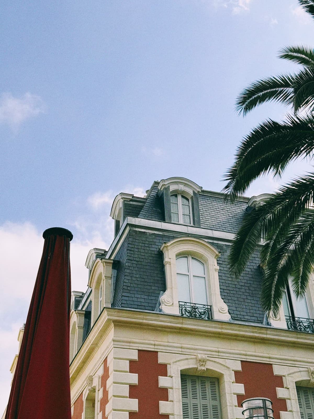 Red brick, slate roofs, a palm leaning in — the palace hotel at full summer