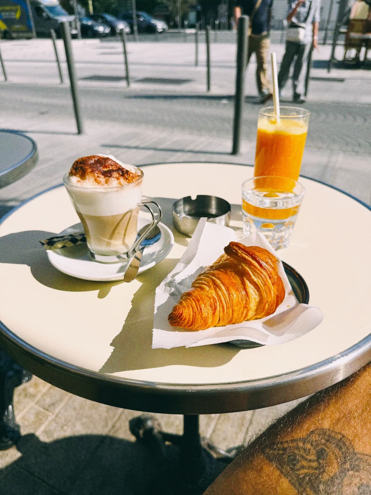 Croissant, coffee, fresh orange — the morning sorted at a sidewalk table