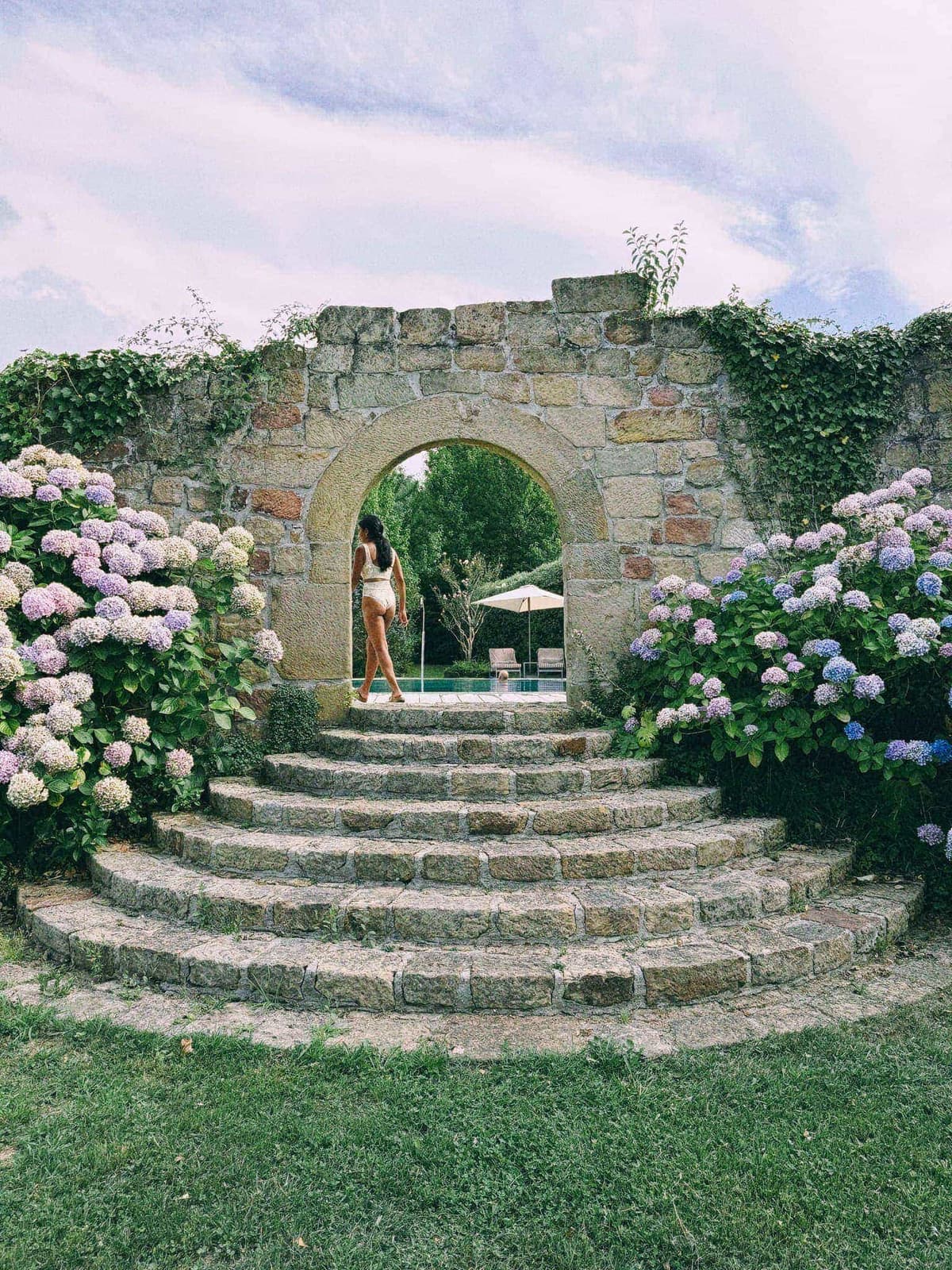 Stone steps fanning down from the garden arch, the pool waiting through it