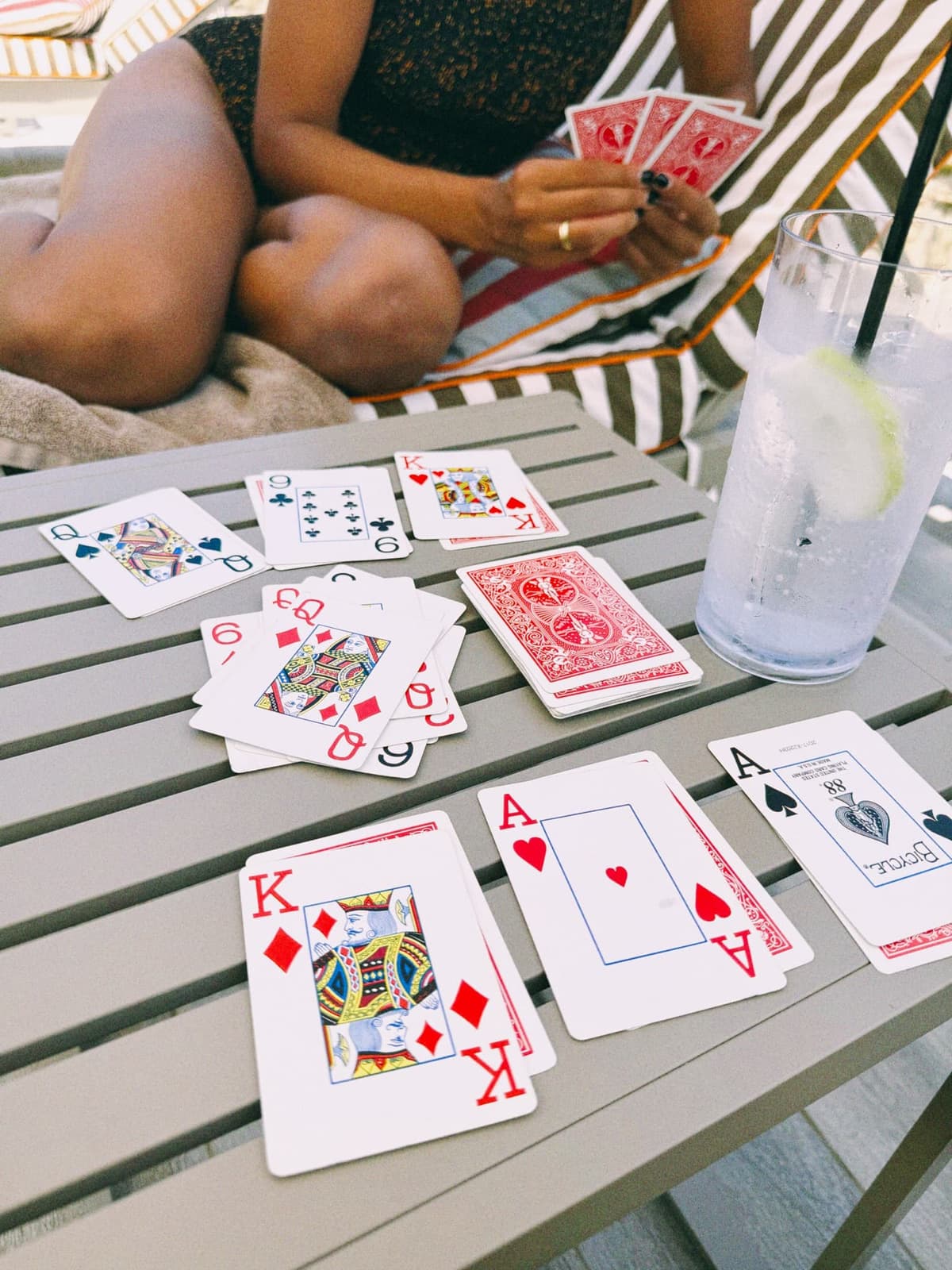 Cards dealt at the poolside table, a gin and tonic keeping score
