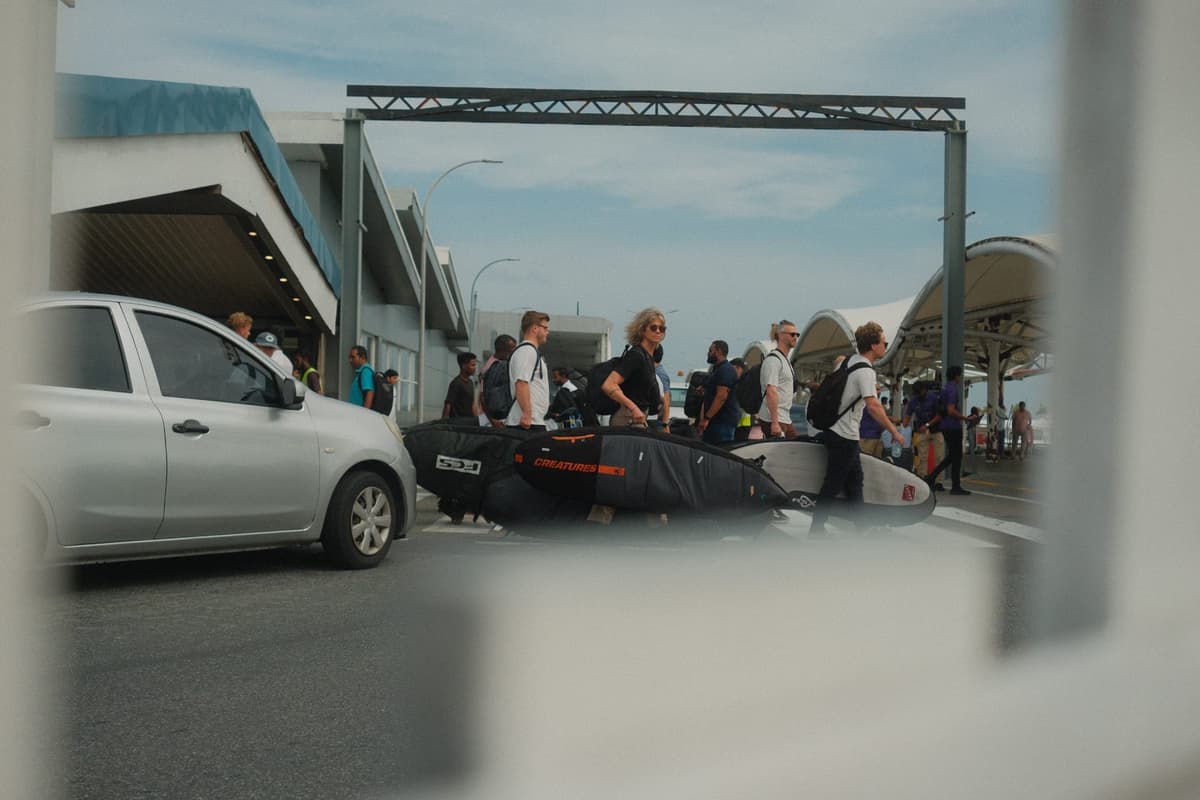Surfers hauling boards through the arrival haze