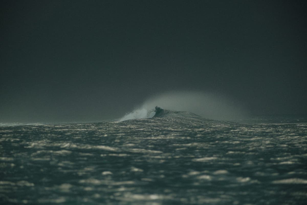 A lone wave curling under a moody dark sky