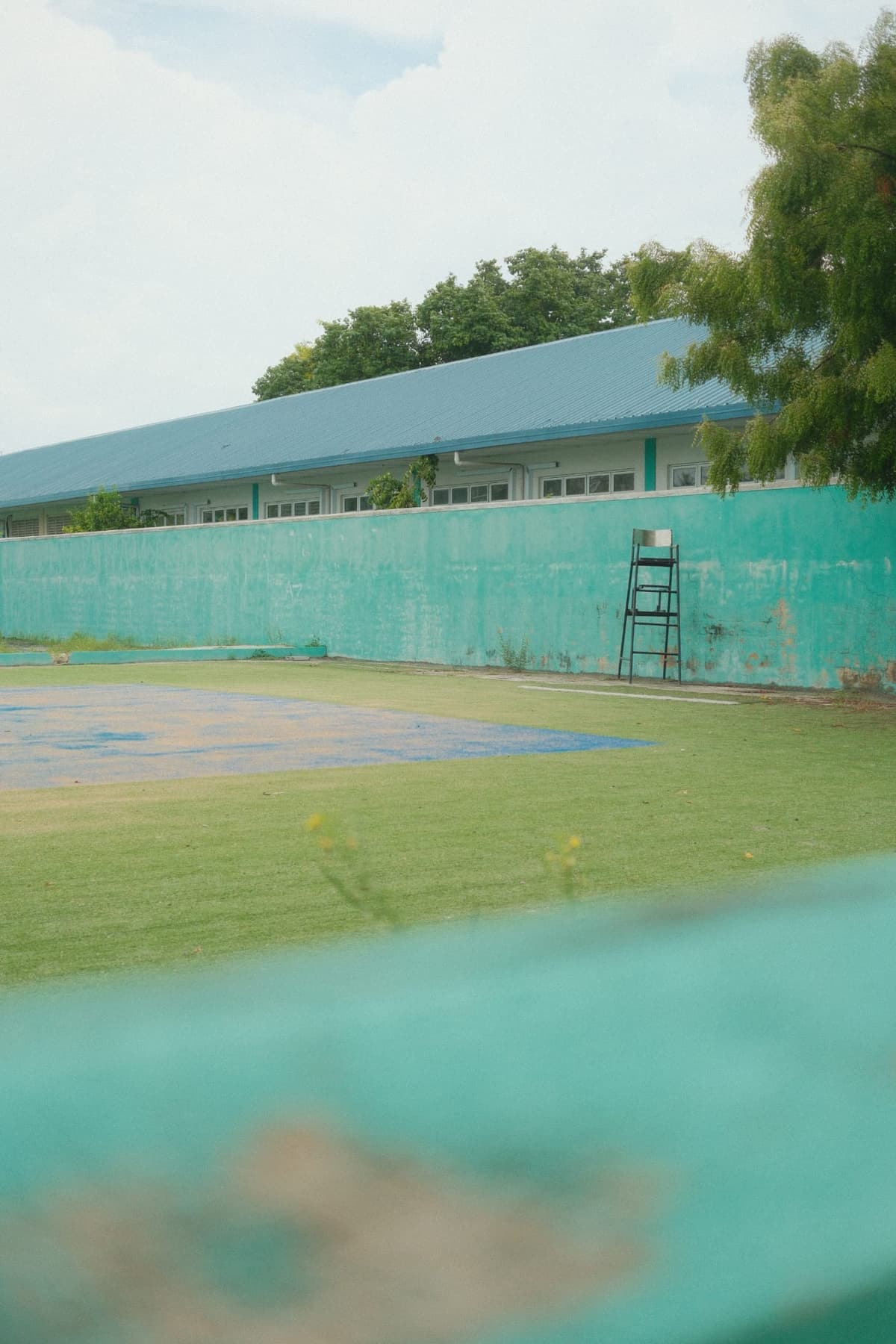 Faded green wall, umpire chair, a court nobody plays