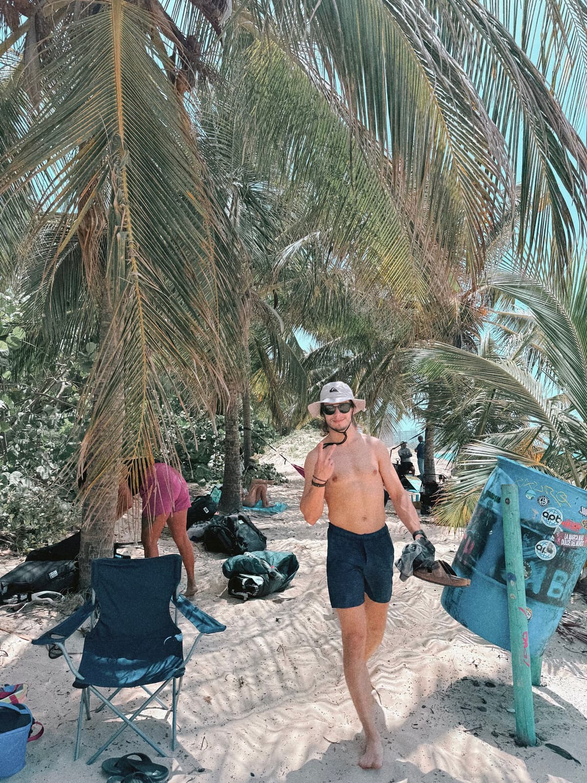 Shade break under the palms, gear and camp chairs strewn across the sand