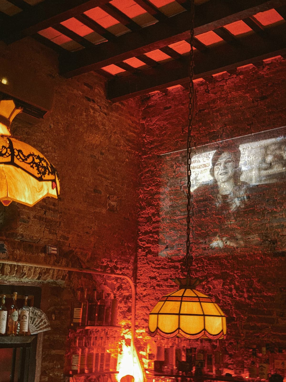 Red glow and stained-glass lamps in a brick-walled bar