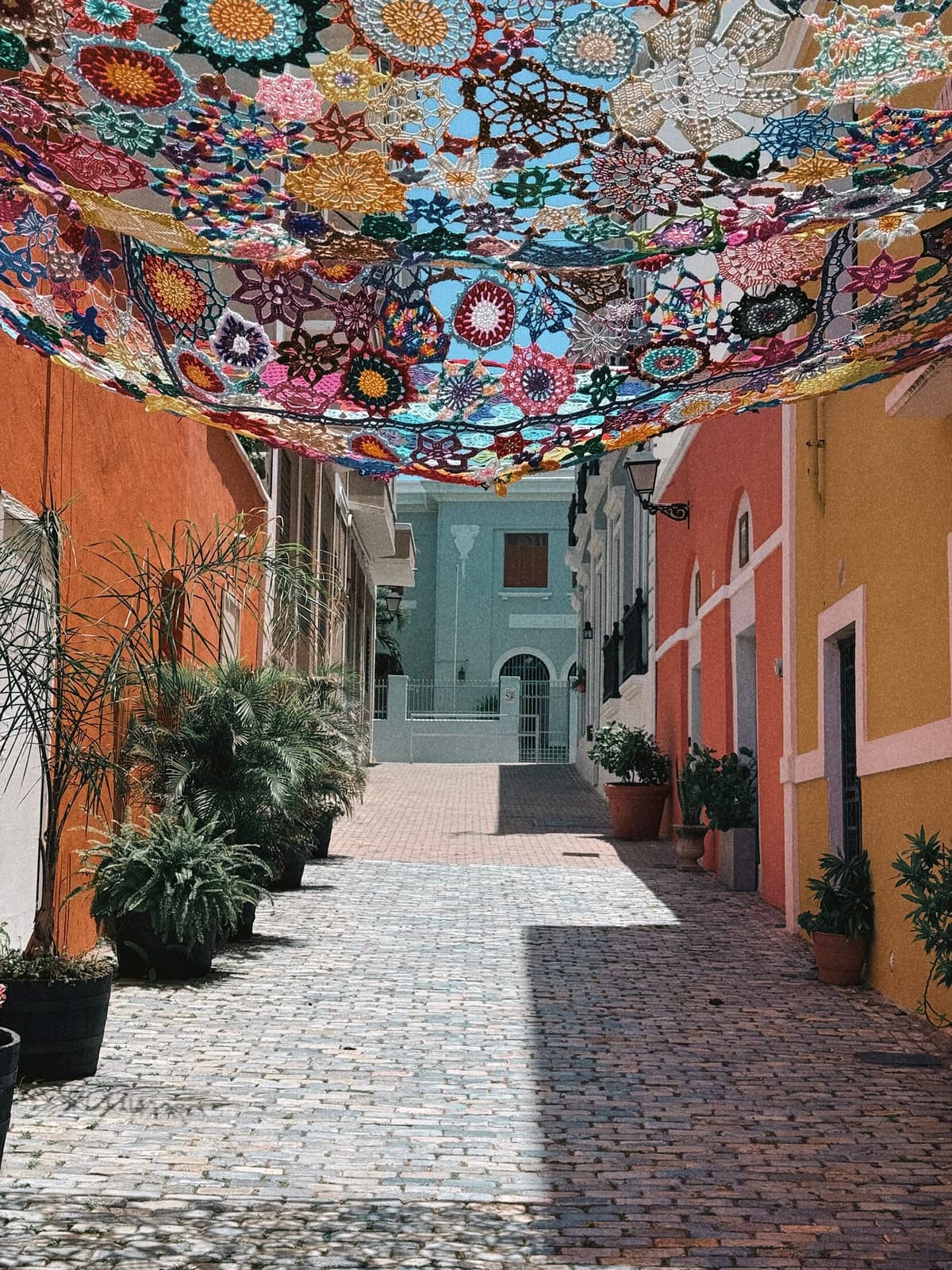 A crocheted canopy strung over a cobblestone alley in Old San Juan