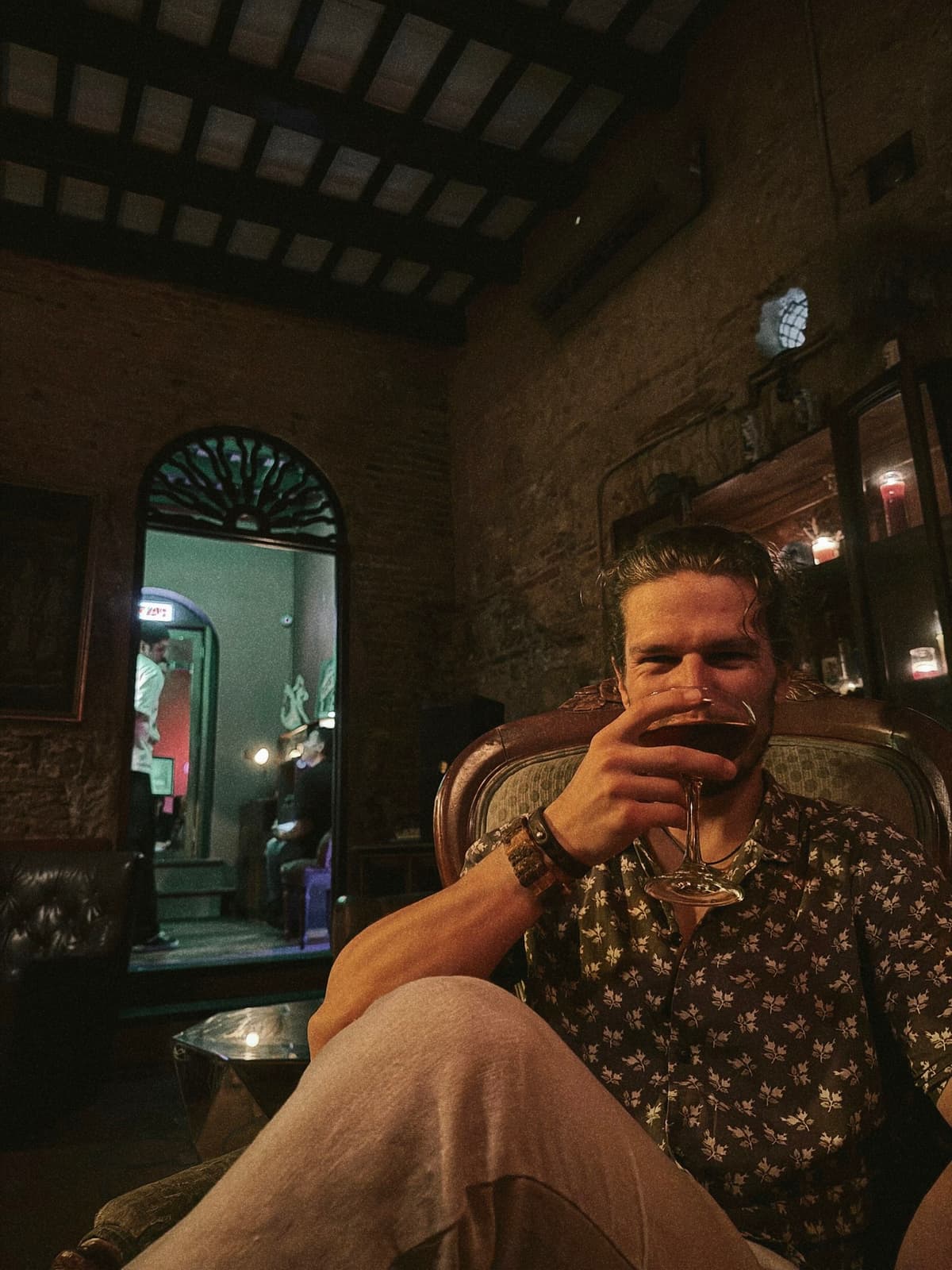 Cocktail in hand in a candlelit brick lounge